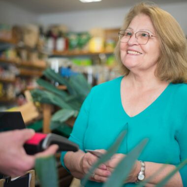 A happy senior woman making a purchase at a local store in Portugal.