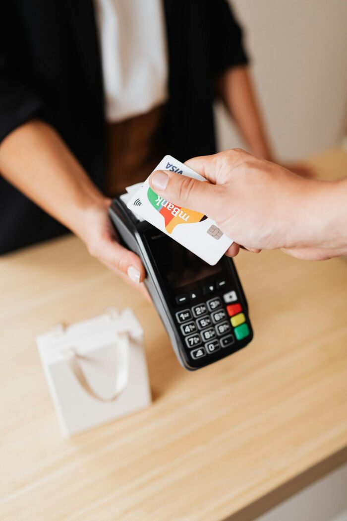 A person using a credit card for contactless payment at a retail counter.