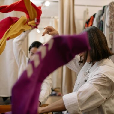 Woman exploring thrift store clothing, showcasing vibrant fashion choices.